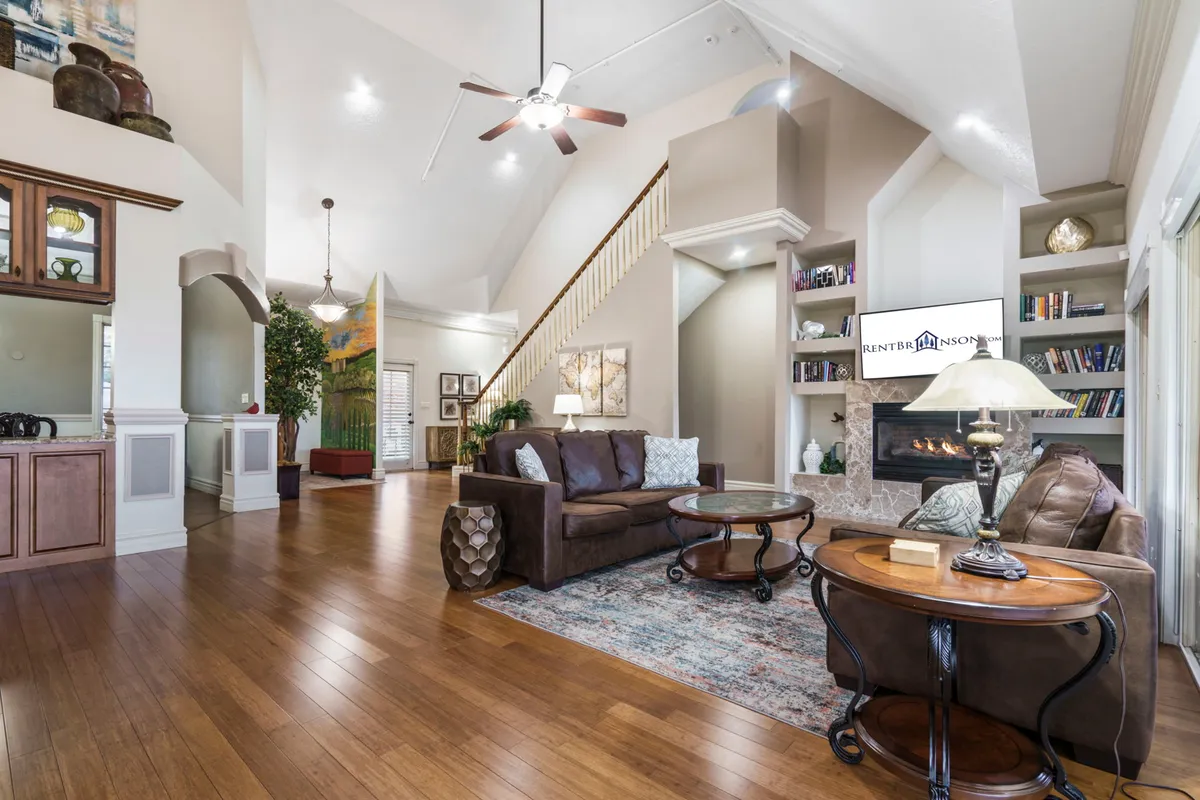A spacious and inviting living area with a cozy sofa, coffee table, fireplace, staircase, and bookshelves. The room is stylishly decorated and perfect for relaxing evenings or entertaining guests by the fire.