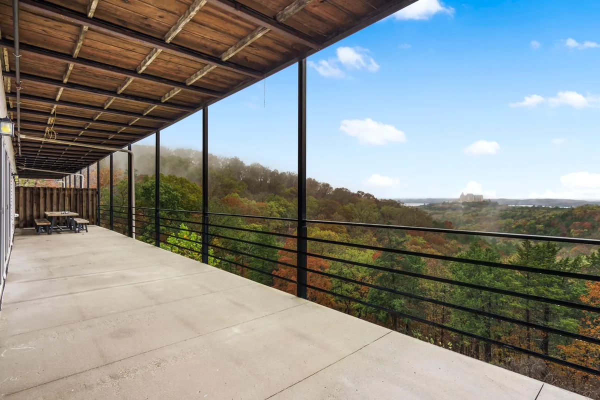 A spacious balcony overlooking distant hills under a clear sky with vibrant, colorful foliage. The space is ideal for relaxing, sharing stories, or enjoying a meal outdoors after exploring local attractions.