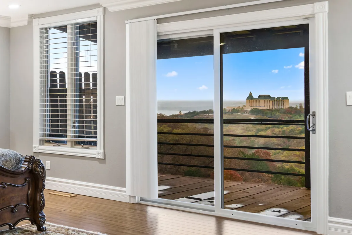 A serene interior scene with a sliding glass door framing breathtaking landscape views. The wooden floor and cozy seating invite guests to enjoy morning coffee, read by the window, and socialize—all while being immersed in the natural beauty of the lake environment.
