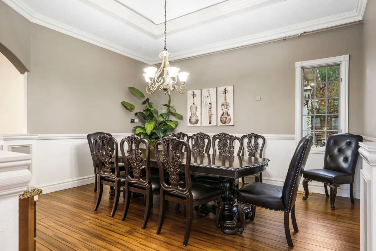 Feature view of the grand dining table set under a chandelier, surrounded by elegant decor including wall art and plants. The atmosphere is sophisticated yet warm, perfect for hosting memorable meals and celebrations.