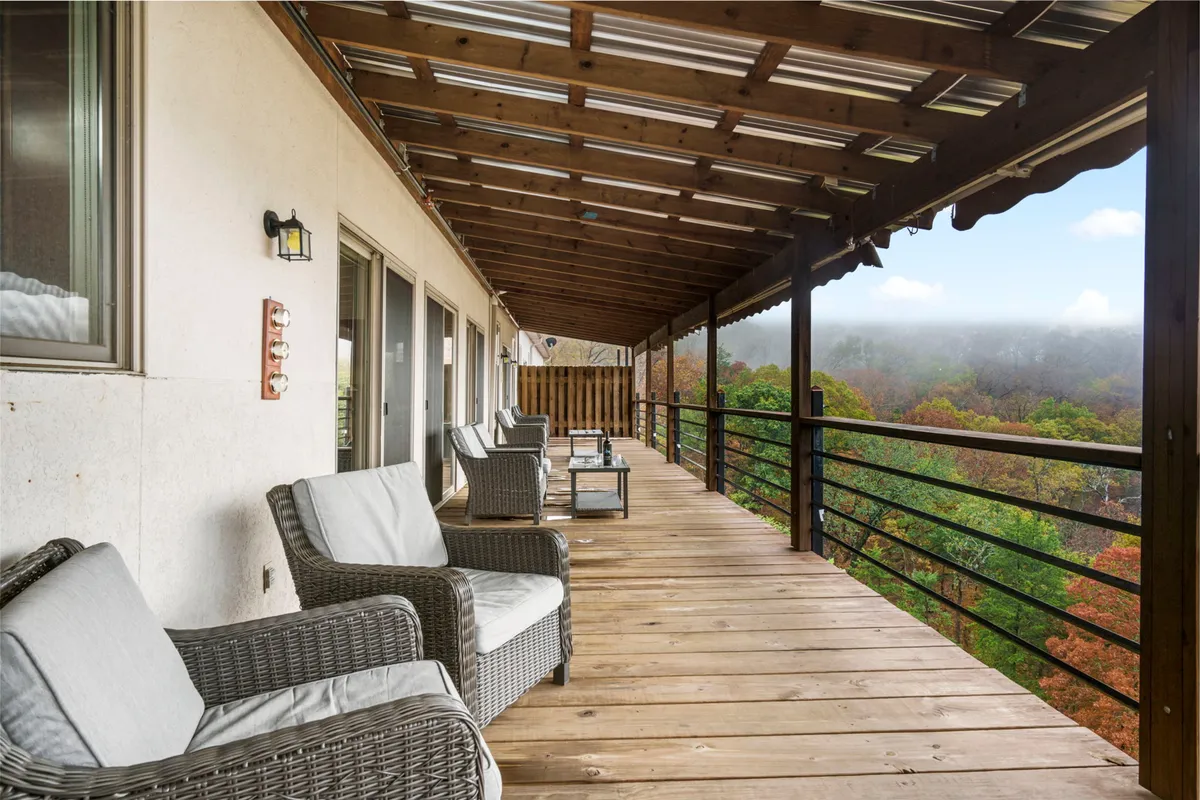 This exterior image features a pair of comfortable wicker chairs positioned on a wooden deck railing. The setting overlooks sweeping mountain views, with soft light hinting at either early morning or late afternoon. The scene exudes tranquility and invites relaxation, perfectly capturing the serenity of outdoor living.