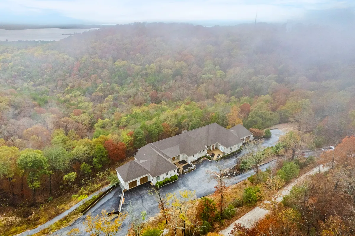 This exterior image captures the large Villa Bellissimo residence surrounded by lush trees and a tranquil, winding driveway. The peaceful setting and expansive outdoor space evoke a sense of privacy, relaxation, and connection to nature—key aspects of luxury lake living.